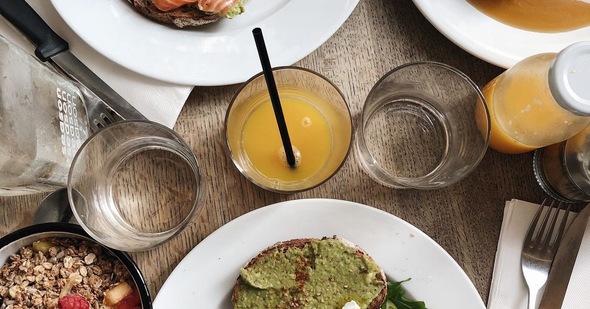 A breakfast table with toast, poached eggs, juice and a bowl of oatmeal