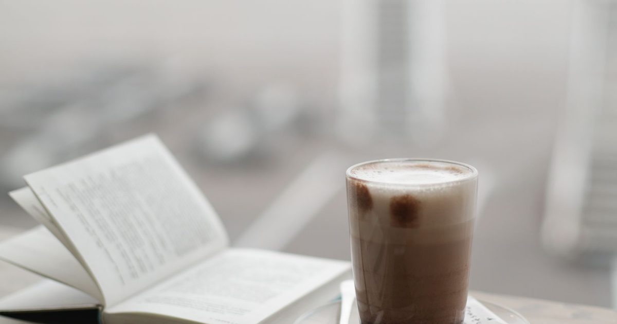 A warm cup of coffee sitting beside a notebook on a table